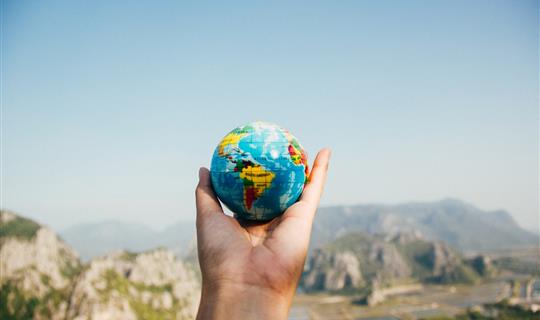 Traveller holding small globe, covered by travel insurance 